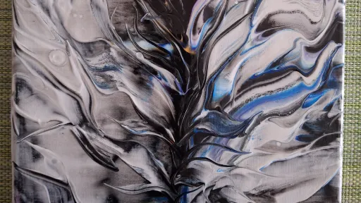 Abstract acrylic pour painting in black, white, and blue.