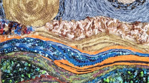 Textile art of a vibrant, textured landscape under a swirling night sky.