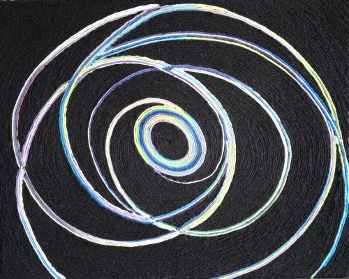 The piece features multicolored woolen threads—in shades of blue, teal, purple, yellow, and white—arranged in intersecting, continuous circular patterns against a solid, textured black background. The threads form concentric and overlapping rings that radiate from a tight central spiral, resembling planetary orbits or swirling cosmic rings.